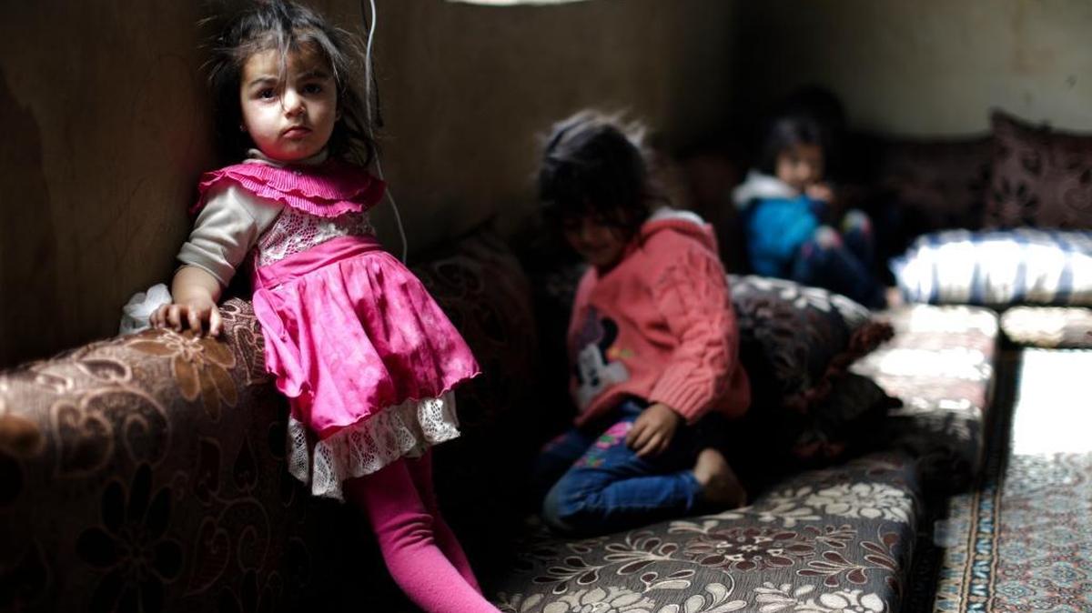Syrian refugee children watch television at their parents tent at an informal refugee camp at Al-Marj town in Bekaa valley in east Lebanon on April 8, 2017. Judith Amber’s poem “No Welcome Mat” was inspired by the refugee crisis.