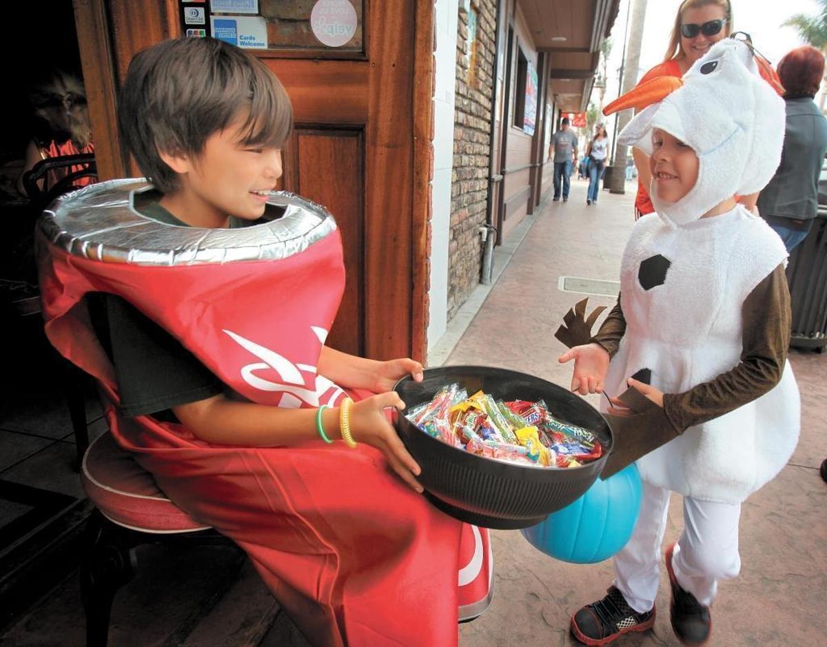 Christian Hunt, 5, of Arroyo Grande, dressed as snowman Olaf from “Frozen,” gets a treat from Toby Matson, who is dressed as a can of Coke, in downtown Pismo Beach.