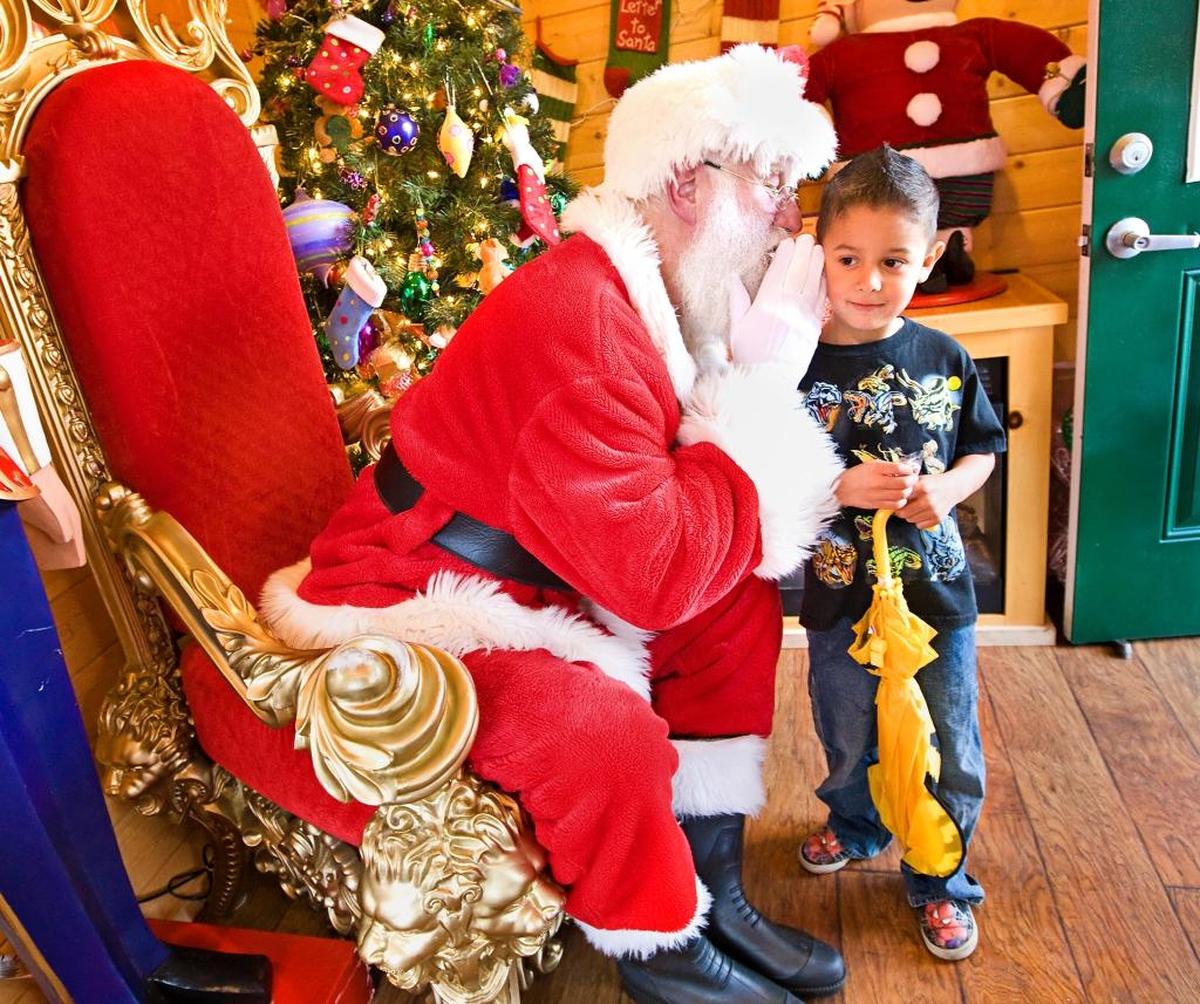 Santa Claus whispers into the ear of Leo Castro, 5, from Arroyo Grande during a visit to Santa’s House in Mission Plaza in 2014.