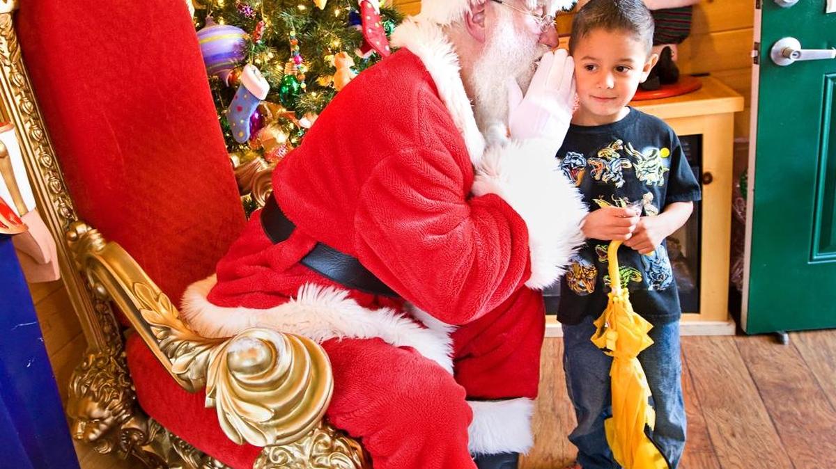 Santa Claus whispers into the ear of Leo Castro, 5, from Arroyo Grande during a visit to Santa's House in Mission Plaza in 2014.