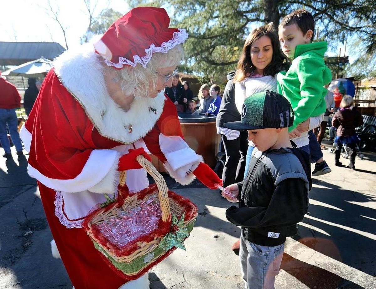 Mrs. Santa Claus, also known as Delma Meyer, hands out candy canes to Evan Echard, 7, while his mom, Mary Echard, and brother Ian, 4, of Atascadero, look on. The Charles Paddock Zoo holds its annual Holiday Magic event on Dec. 16.