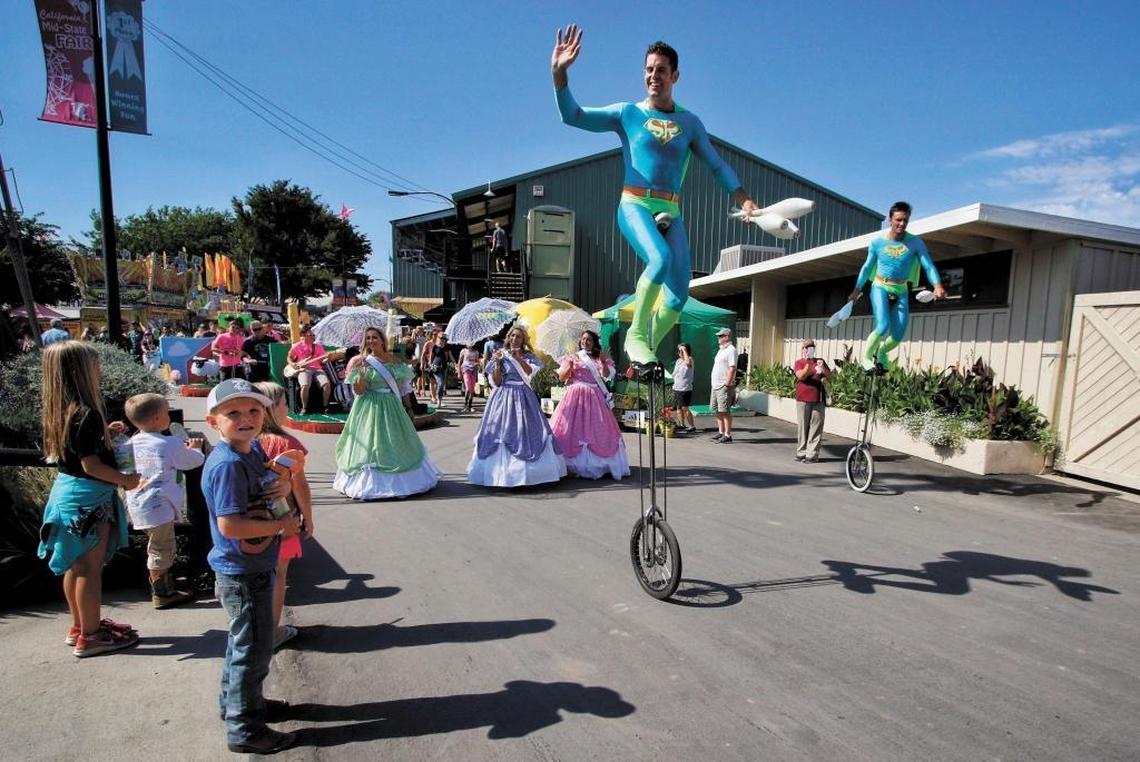 The Midway Spectacular parade makes its way through the California Mid-State Fair led by the unicycling juggling duo Something Ridiculous.