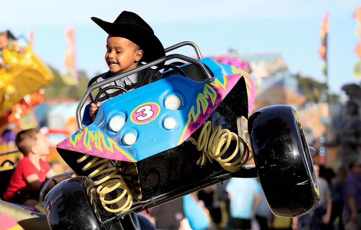 Fairgoers enjoy free carnival rides on opening day of the California Mid-State Fair in Paso Robles, Wednesday, July 17, 2019. Uri Torres-Granados, 4, of Paso Robles really enjoys the Baja Buggies ride.
