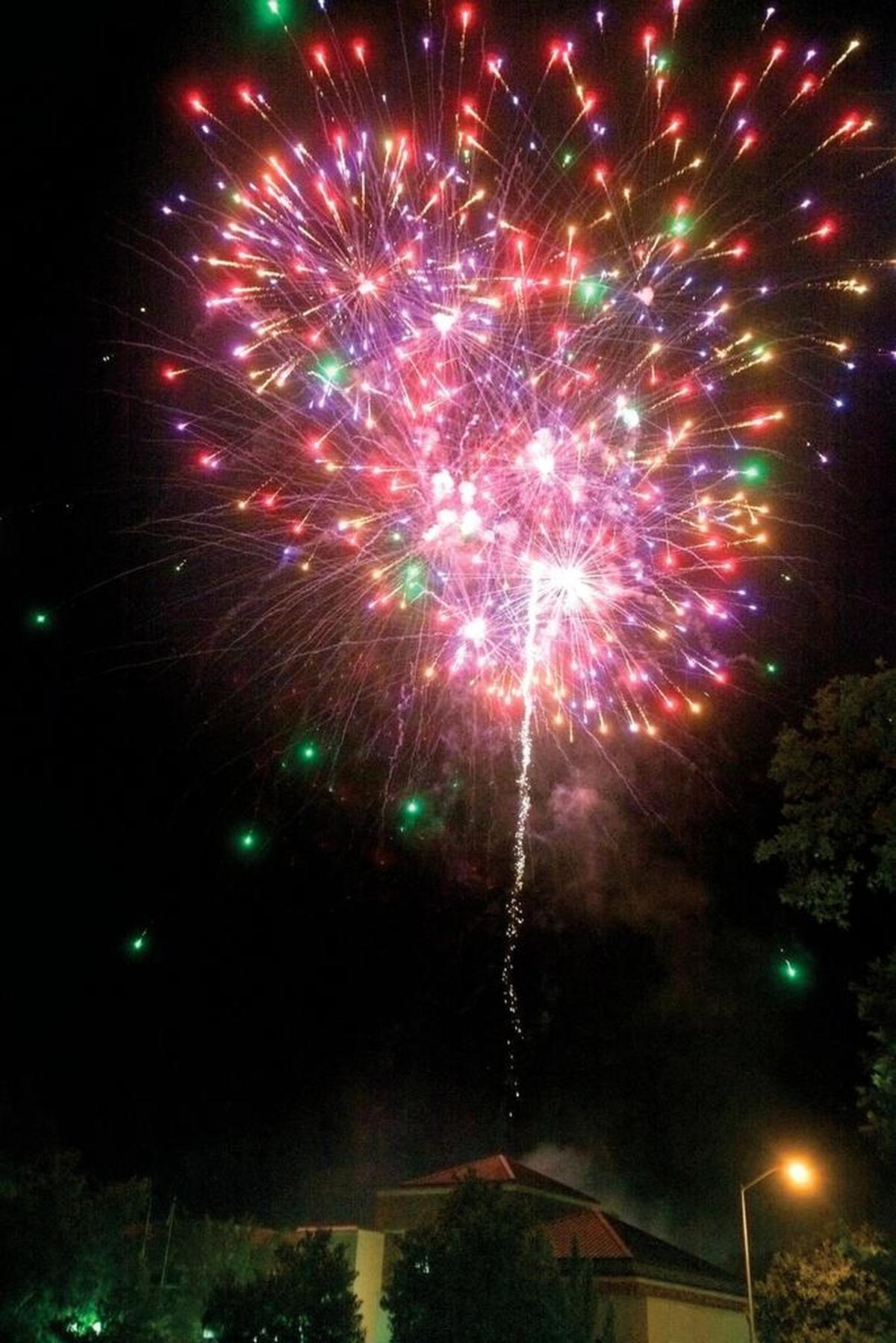 Fireworks explode behind the Paso Robles City Library on July 4, 2014, as a large crowd watches from nearby Downtown City Park.