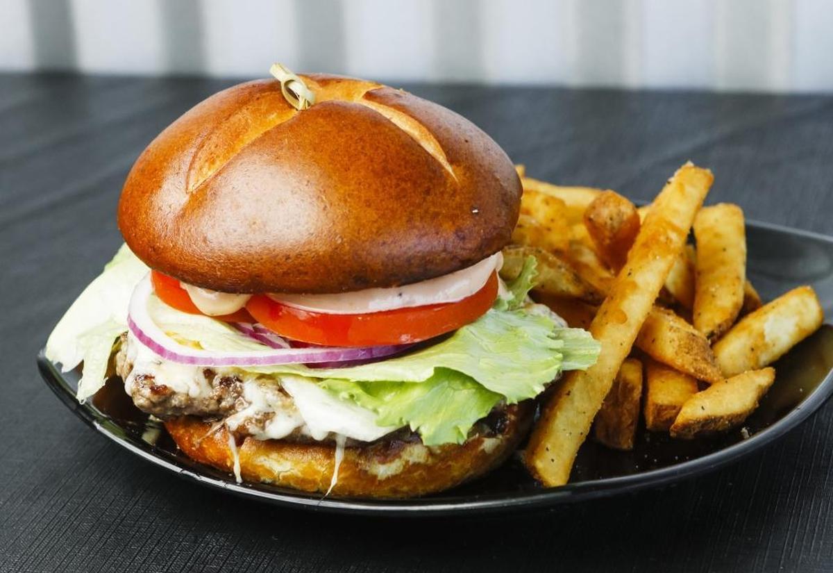 A cheeseburger is served on a preztel bun with a side of fries at Flavor Factory in Morro Bay.