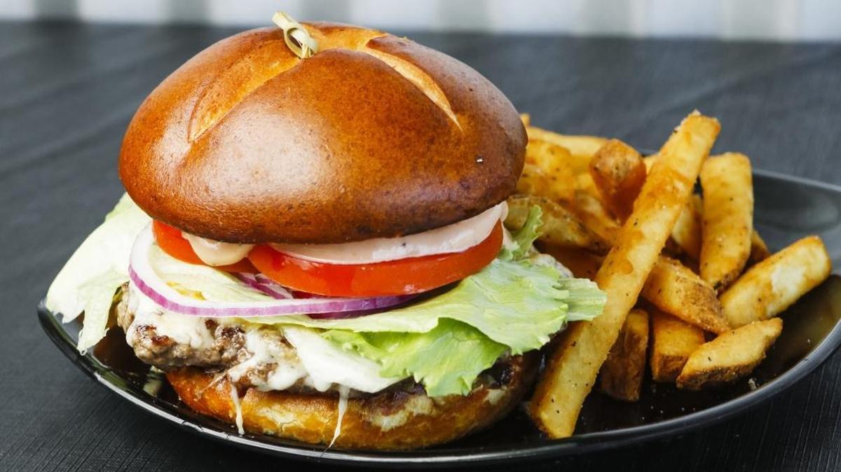 A cheeseburger is served on a preztel bun with a side of fries at Flavor Factory in Morro Bay.