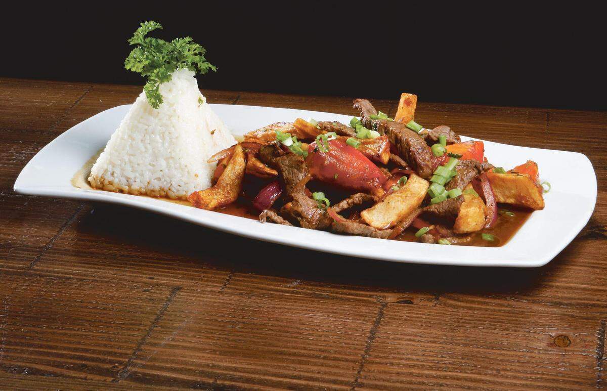 Lomo Saltado, free-range natural top sirloin strips stirred fried with organic fresh tomatoes, red onions, Peruvian spices, aji amarillo, soy sauce, potatoes, parsley served with Peruvian White Rice.