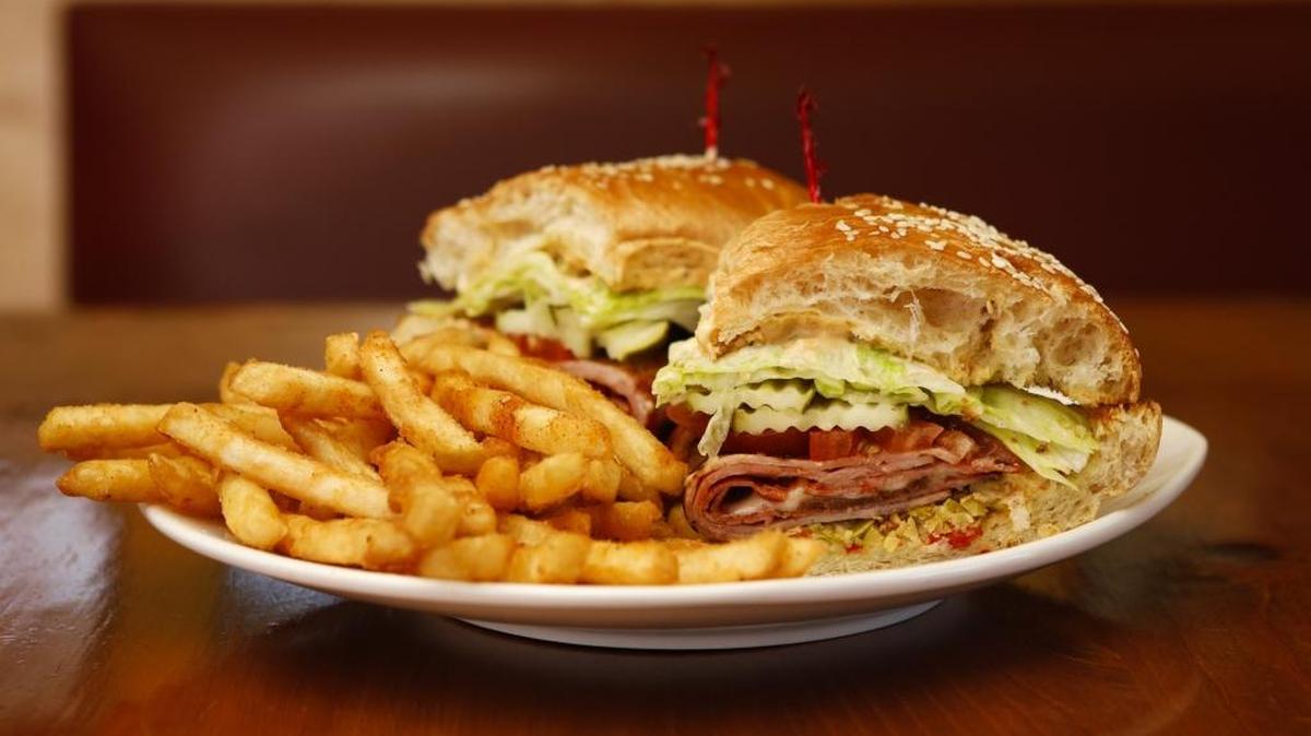 A muffaletta, served with french fries at Bon Temps Creole Café in San Luis Obispo, features ham, bacon, sausage and olive salad on a sesame loaf.