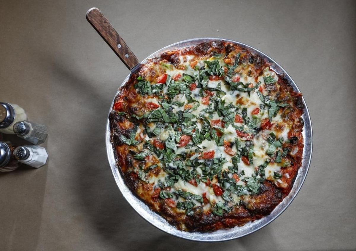 A pizza at Nardonne’s La Famiglia Pizzeria, which has locations in Atascadero and Los Osos, features tomatoes, basil, olives, onion, artichoke hearts and bell peppers.
