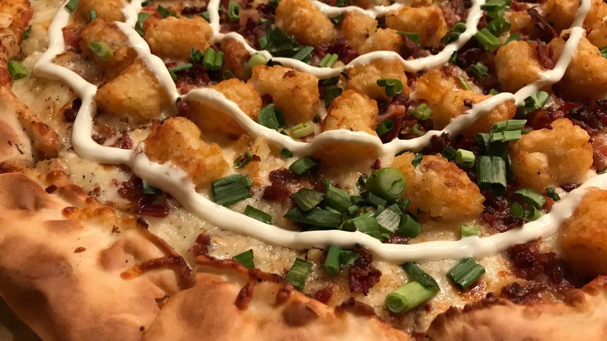 At Woodstock’s Pizza in San Luis Obispo, the Too Loaded So Baked pizza is topped with creamy garlic sauce, mozzarella cheese, tater tots, crispy bacon, fresh green onions and a sour cream drizzle.
