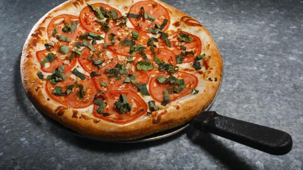 Margherita pizza with fresh basil, thinly sliced tomatoes and garlic is a popular menu item at Gino’s Pizza, which has locations in Pismo Beach and San Luis Obispo.