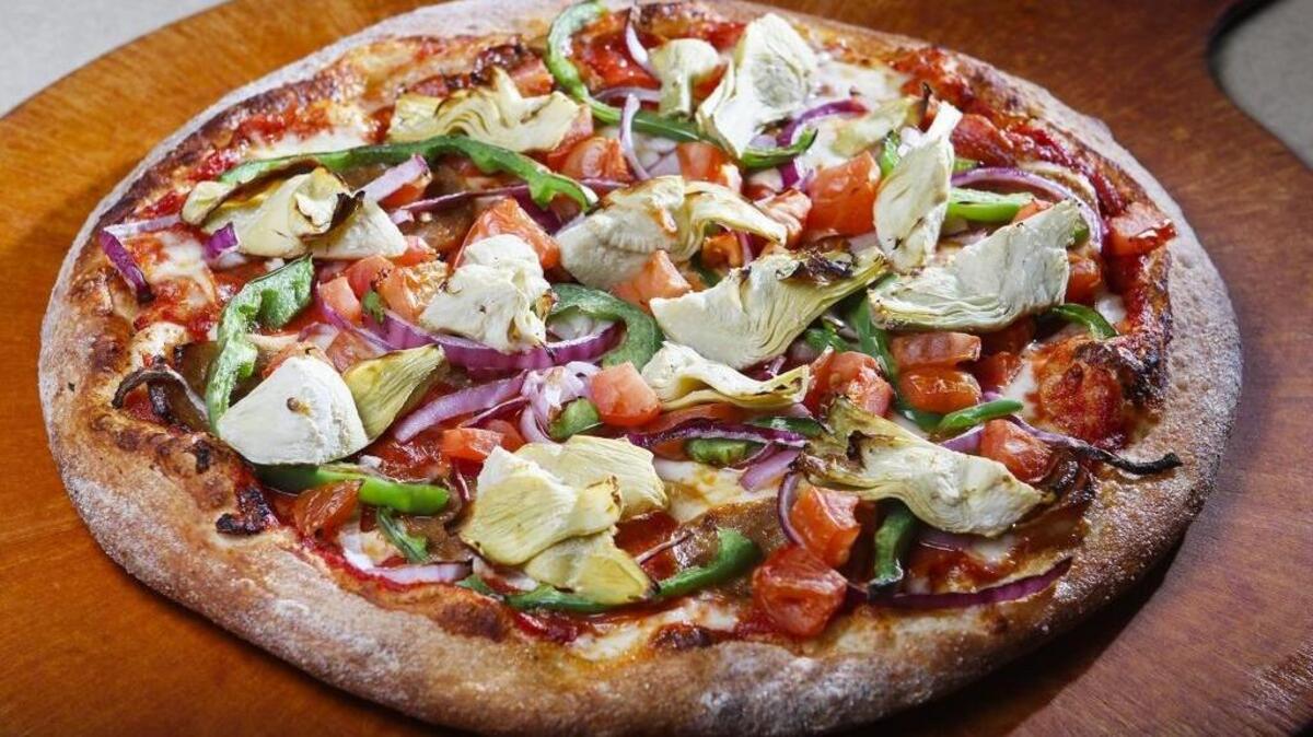 Toppings on the Surfer’s Friend pizza at Nichols Pizza-N-Grill in Los Osos include red onion, bell pepper, tomato, artichoke, pepperoni and sausage.