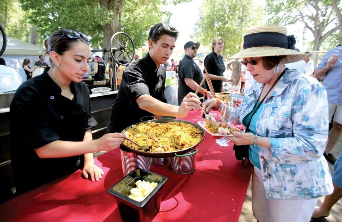 Laura Tremblay of San Luis Obispo samples a traditional seafood, chicken and chorizo paella served by Paso Robles Culinary Institute chef graduates Marina Perry, left, and Noah Yoshida at Paso Pinot and Paella Festival in 2013. The festival returns to Templeton Park in June 2017.