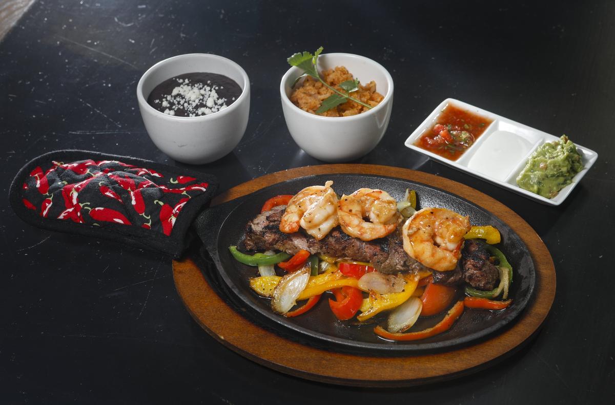 Surf-and-turf fajitas are served with grilled peppers, onions, refried black beans, Mexican rice and salsa, sour cream and guacamole at La Esquina Taqueria in downtown San Luis Obispo.