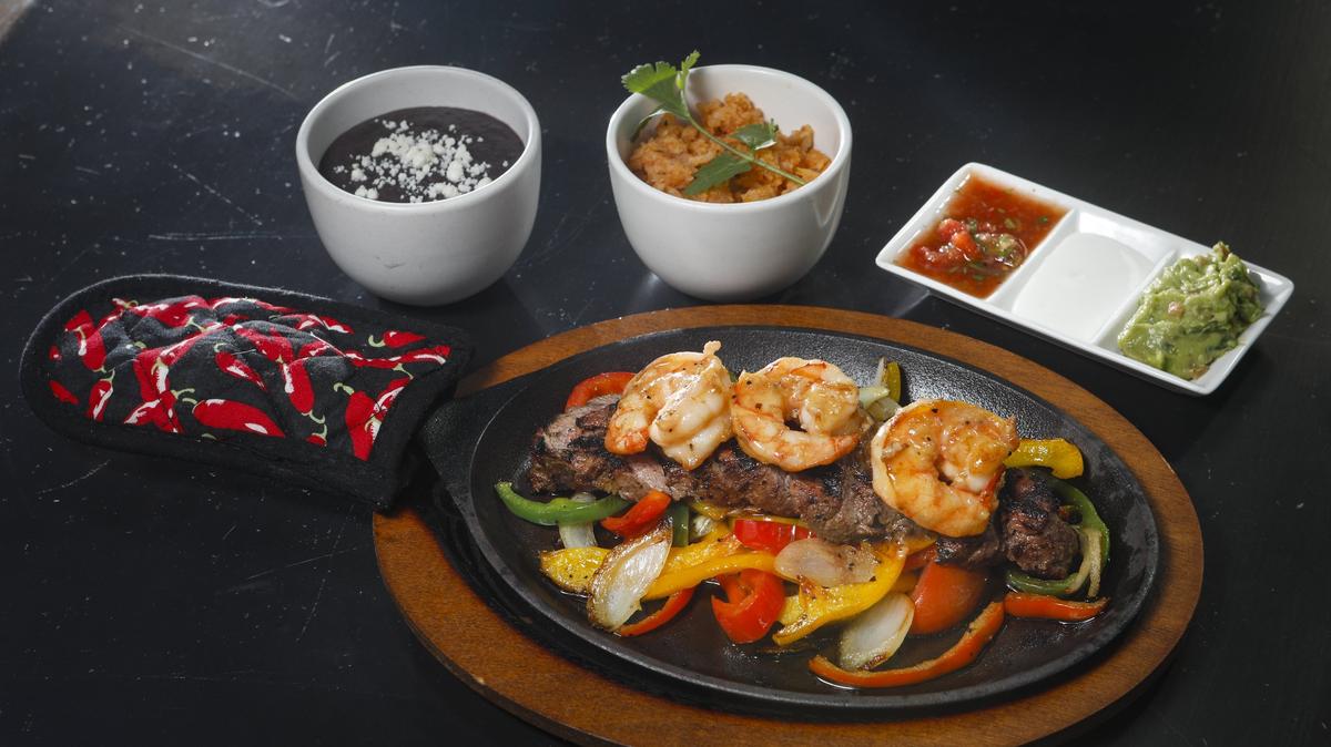 Surf-and-turf fajitas are served with grilled peppers, onions, refried black beans, Mexican rice and salsa, sour cream and guacamole at  La Esquina Taqueria in downtown San Luis Obispo.