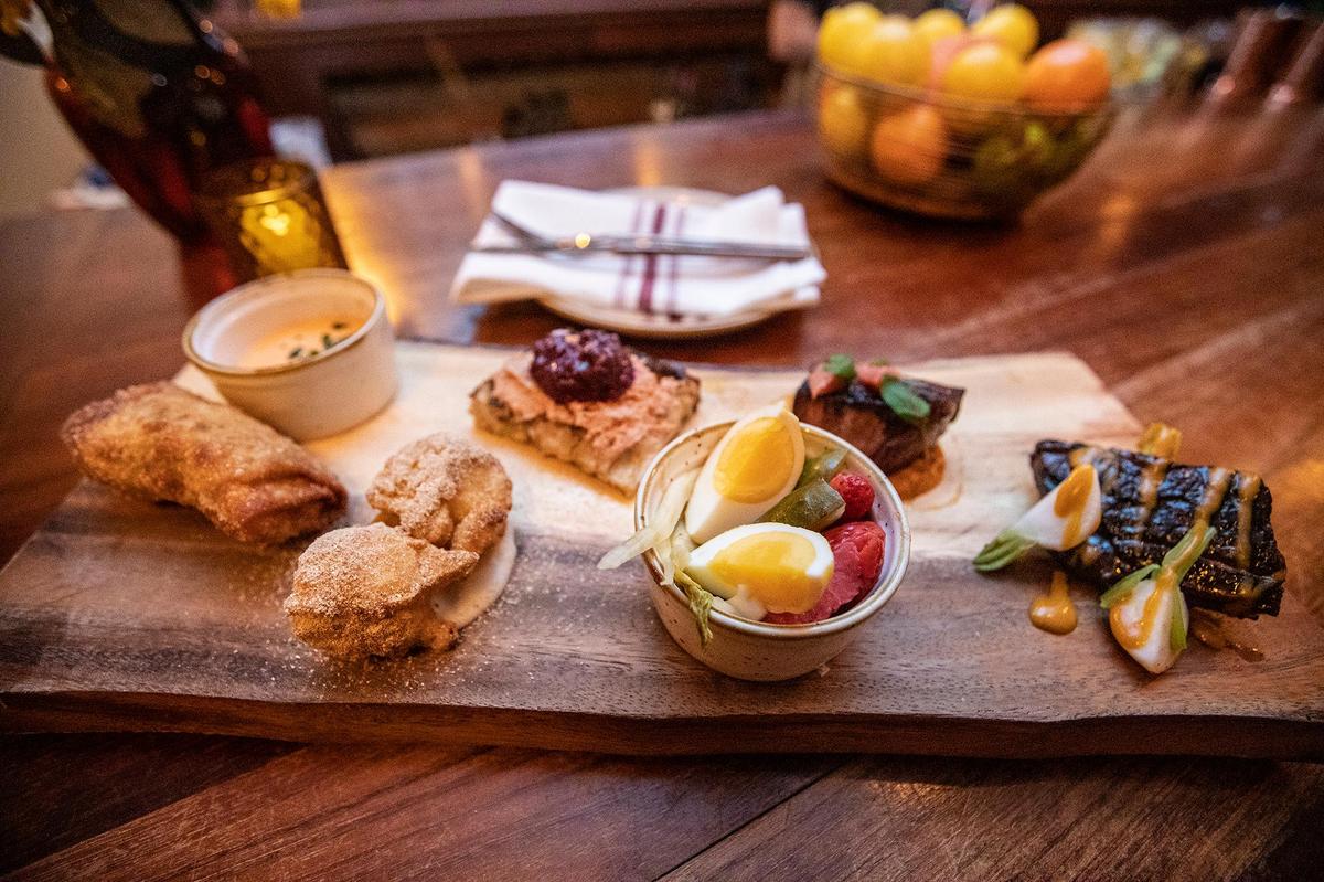 A new cocktail bar with “good eats and tunes” has opened in SLO. Highwater, the venture of Robin Kirk Wolf and Matt Hanson, launched at the old Sidecar location on Broad Street, a couple of doors down from Big Sky Cafe. Here, some of the food is served on a wood plank, from left, Reuben lumpia, mighty cap mushroom doughnuts, grilled pork belly and barbecue beef short riblets.