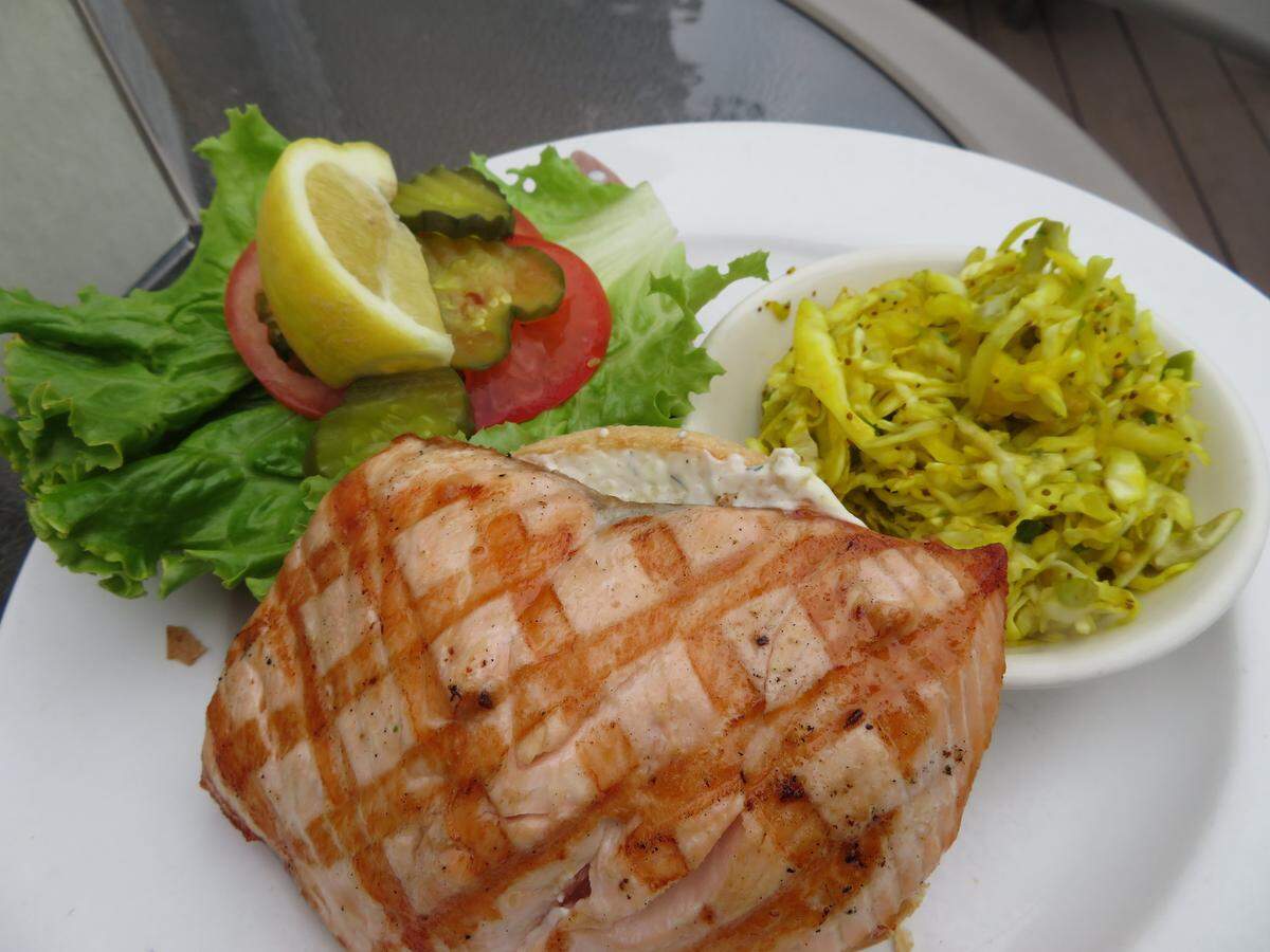 The salmon sandwich at Bayside Café in Morro Bay features char-broiled salmon filet on a brioche bun with house-made tartar sauce, lettuce, tomato and dill pickle chips.