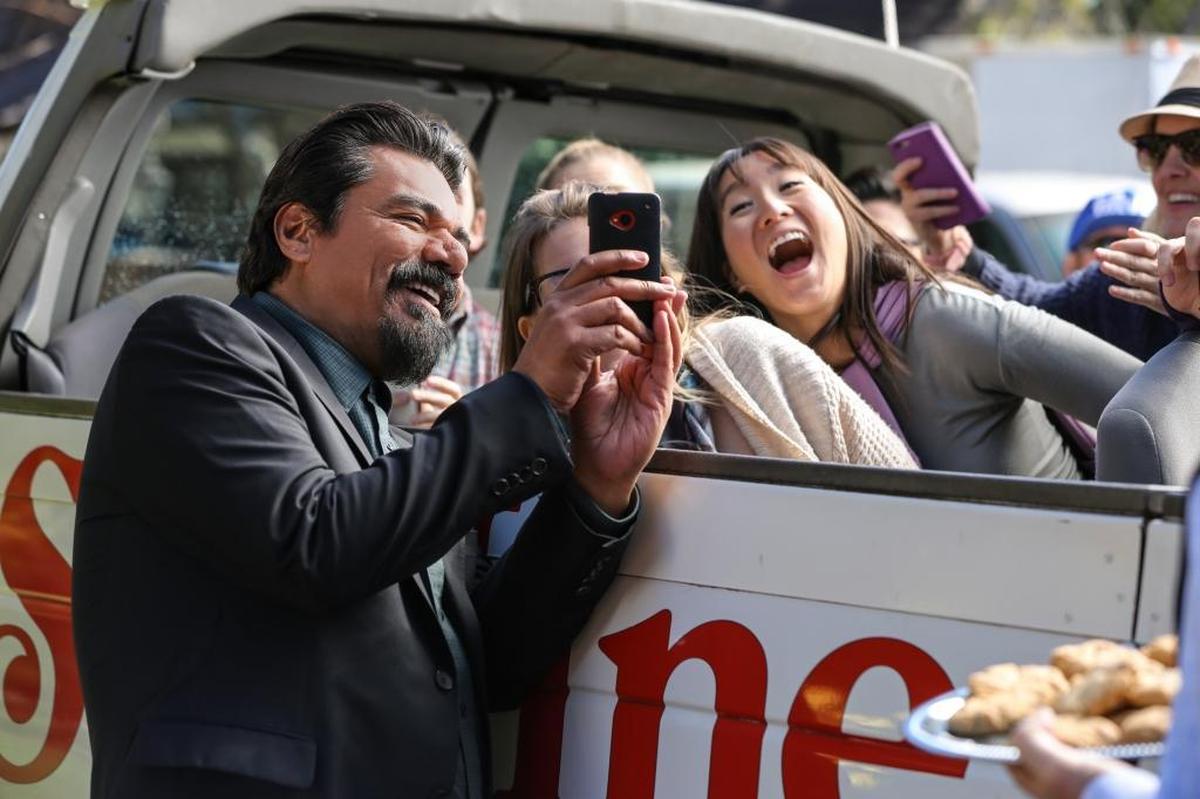 George (George Lopez) poses for a few selfies with fans in a scene from “Lopez” on TV Land.​