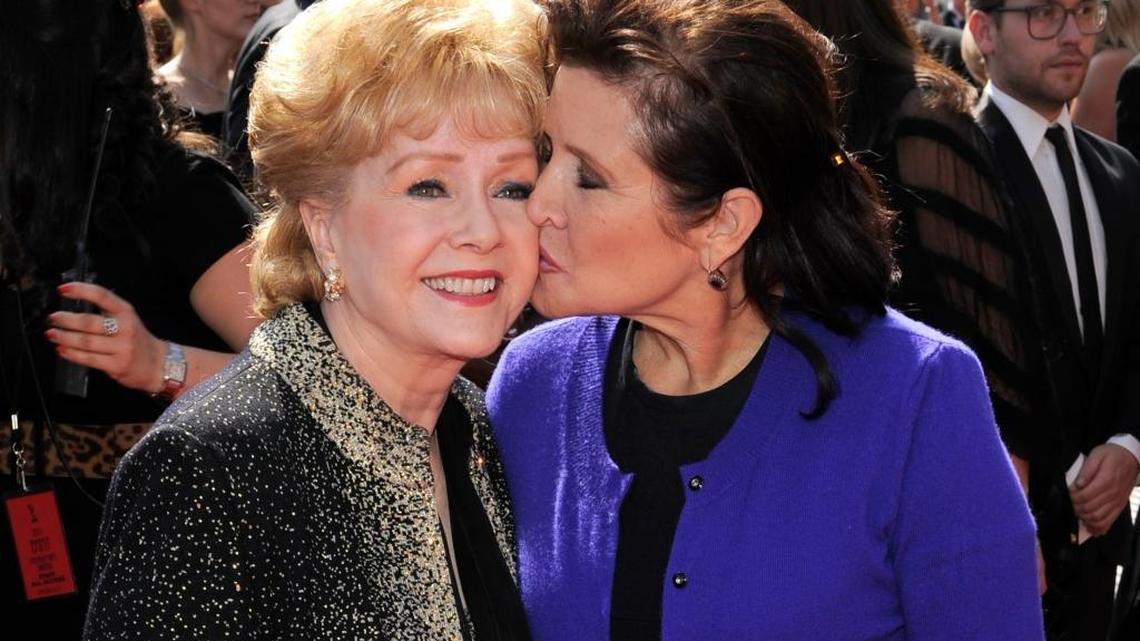 Carrie Fisher kisses her mother, Debbie Reynolds, as they arrive at the Primetime Creative Arts Emmy Awards in Los Angeles in 2011. The two died in late December.