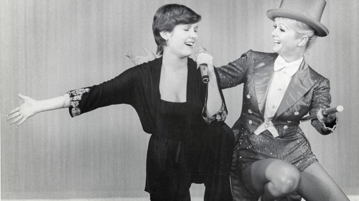 Carrie Fisher sings as her mother, Debbie Reynolds, smiles. The two are the focus of the HBO documentary “Bright Lights: Starring Carrie Fisher and Debbie Reynolds,” screening March 15 as part of the San Luis Obispo International Film Festival.