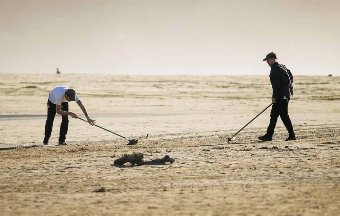 Members of the production crew sweep the beach before shooting a scene for Showtime’s “The Affair” near Morro Rock in Morro Bay.