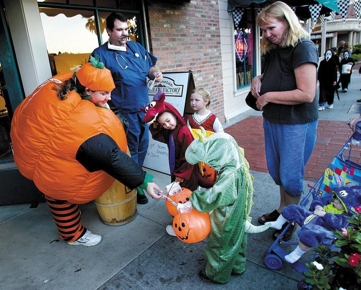 Jeff and Brooke Roby give out candy to trick-or-treaters in front of Rocky Mountain Chocolate Factory in downtown Paso Robles on Halloween.