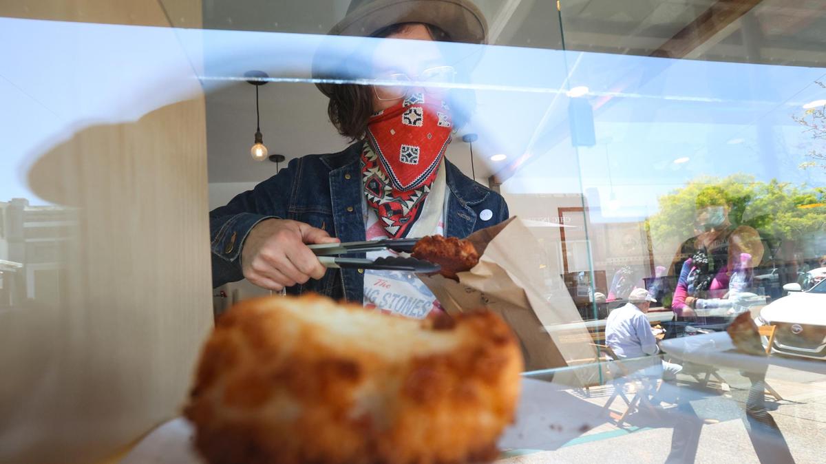 Chris Beland, barista at Mule Bakery and Cafe, serves up a pastry at the new to-go window.