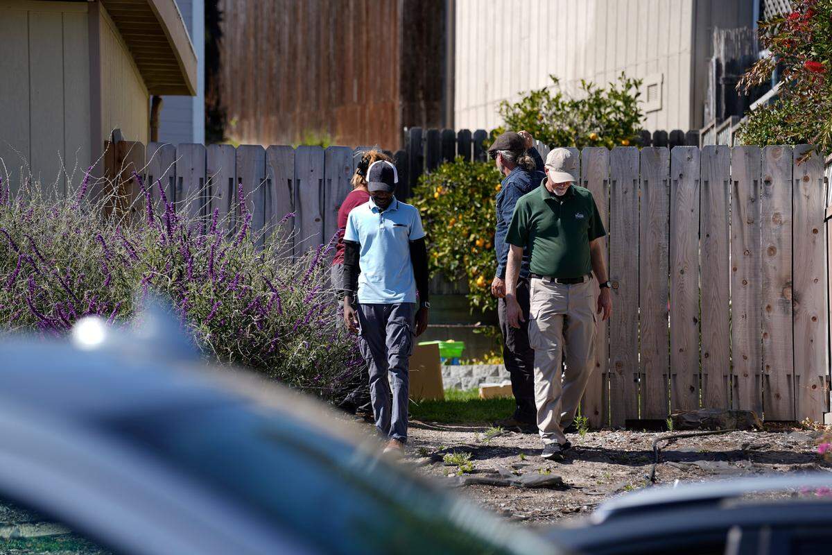 A group including environmental engineer Tim Nelligan, center right, walk from the backyard of the property next door to Susan Flores’ home on East Branch Street in Arroyo Grande as part of the Kristin Smart investigation on May 6, 2026. Susan Flores is the mother of Paul Flores, who was convicted of Smart’s murder in 2022.