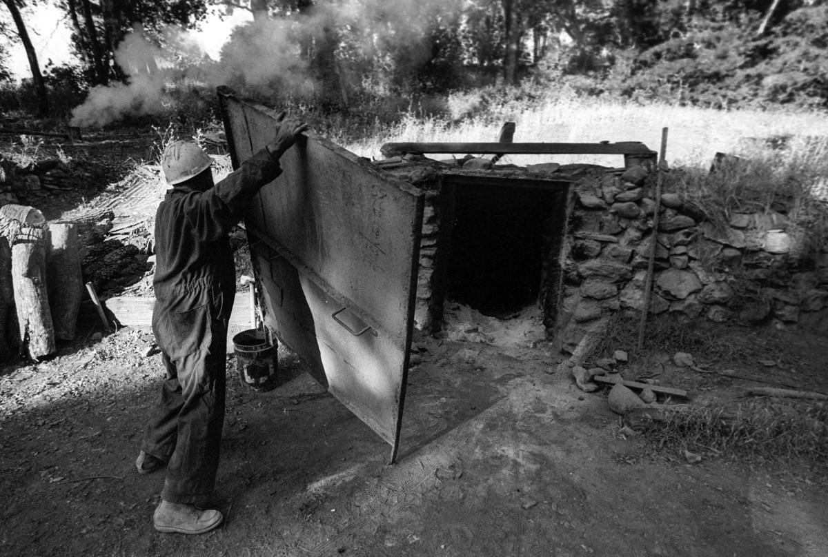 Atillio Busi places a door over a charcoal kiln as oak wood is converted on June 12, 1981