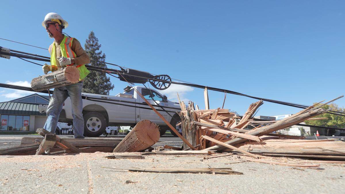 Don Hedlund with AT&T loads hunks of wood as workers cleared at least nine utility poles and lines that were toppled by a truck towing an oversized load on El Camino Real in Atascadero on Monday, Oct. 27, 2025.