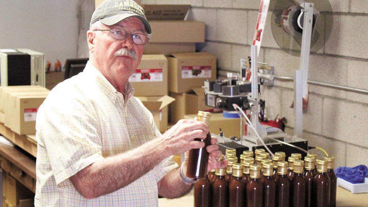 John Linn shows bottles of the product his company will ship to Knott's Berry Farm in Buena Park before they're labeled Thursday at Linn's production facility on Village Lane in Cambria.