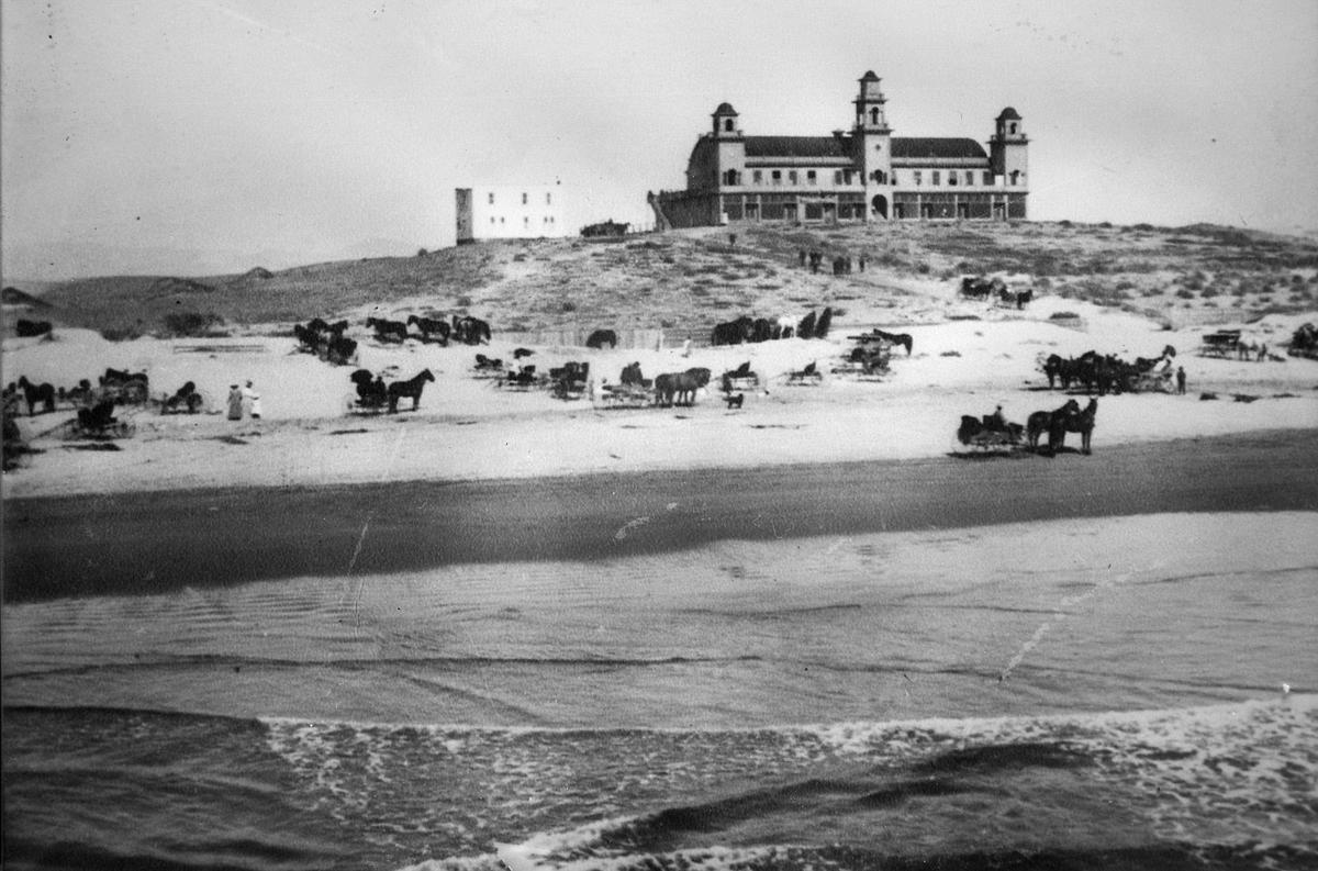 Midway between Oceano and Oso Flaco Lake, one of three speculator-driven communities was mapped out on the dunes. It was advertised as the “future Atlantic City of the Pacific.” La Grande Beach had 8,000 lots that extended two miles into the dunes. The trio of towers topped a building with gift shops and offices on the ground floor and a second floor dance hall complete with grand piano. A pier allowed steamers to tie up offshore. This photo was from the grand opening on July 4, 1907. The biggest problem was access. When Arroyo Grande Creek flooded, the community was cut off for days. Thin-wheeled buggies and early cars were difficult to move through shifting sand. The boom ended with a crash and by 1915 the building was in ruins. The structure was torn down in 1921. The land is now owned by the State of California, San Luis Obispo County and some private owners. Information from the book “The Dunites” by Norm Hammond.