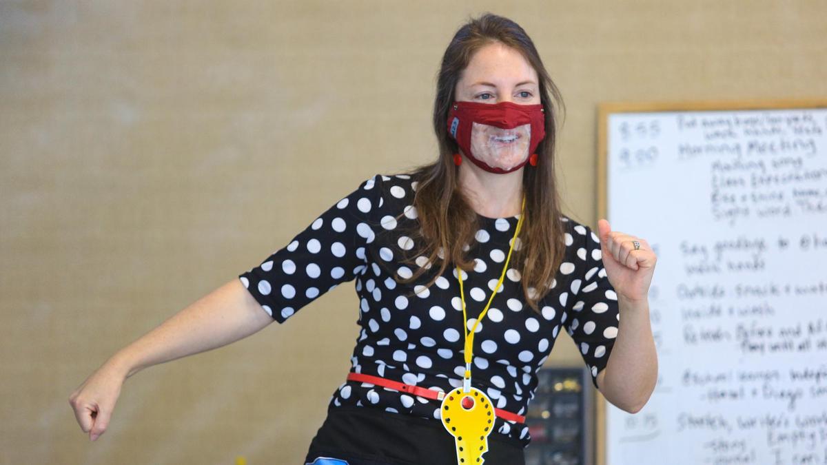 Teacher Shelby West wears a see-through mask and greets her transitional kindergarten kids back to Shell Beach Elementary School as they sing to start the day.
