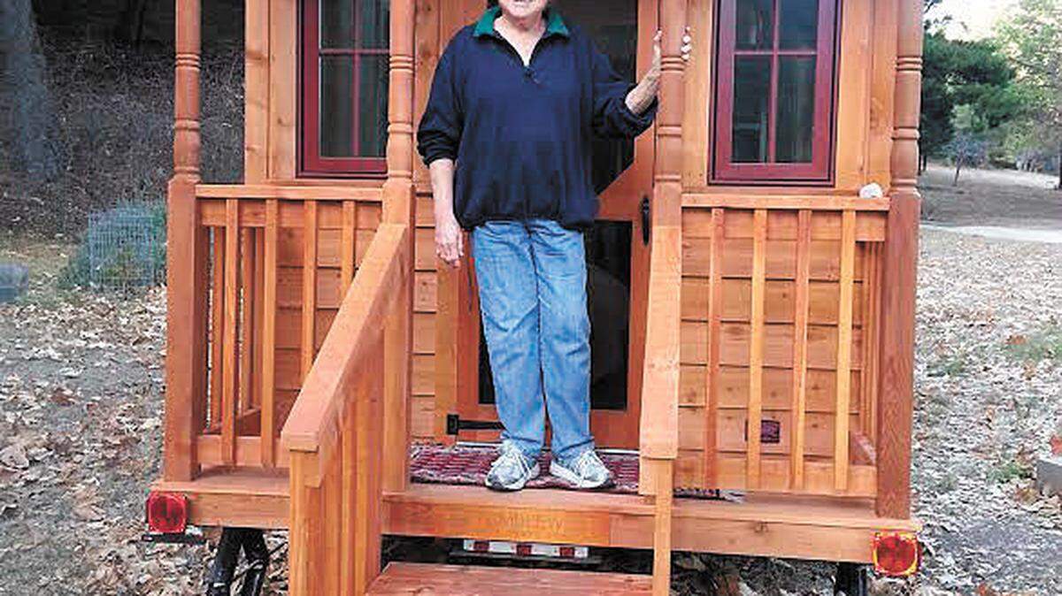 Bette Presley stands on the porch of her 166-square-foot cabin.