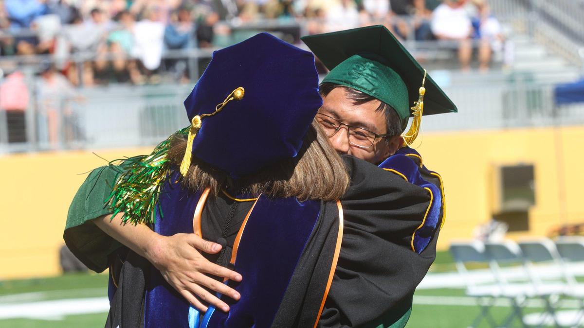 Stephen Chang gets a hug from faculty member Ann De Lay at Cal Poly graduation. The California Polytechnic State University began a series of graduations with the College of Agriculture, Food and Environmental Sciences at Spanos Stadium June 11, 2022.
