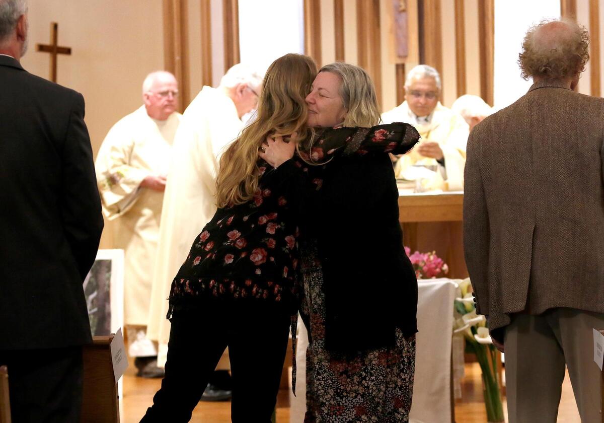 Family members hug during the service as Santa Rosa Catholic Church celebrated the life of the Rev. Mark Stetz with an overflow memorial Thursday, March 31, 2022, in Cambria. Stetz, 63, whom almost everybody called “Father Mark,” died on March 13.