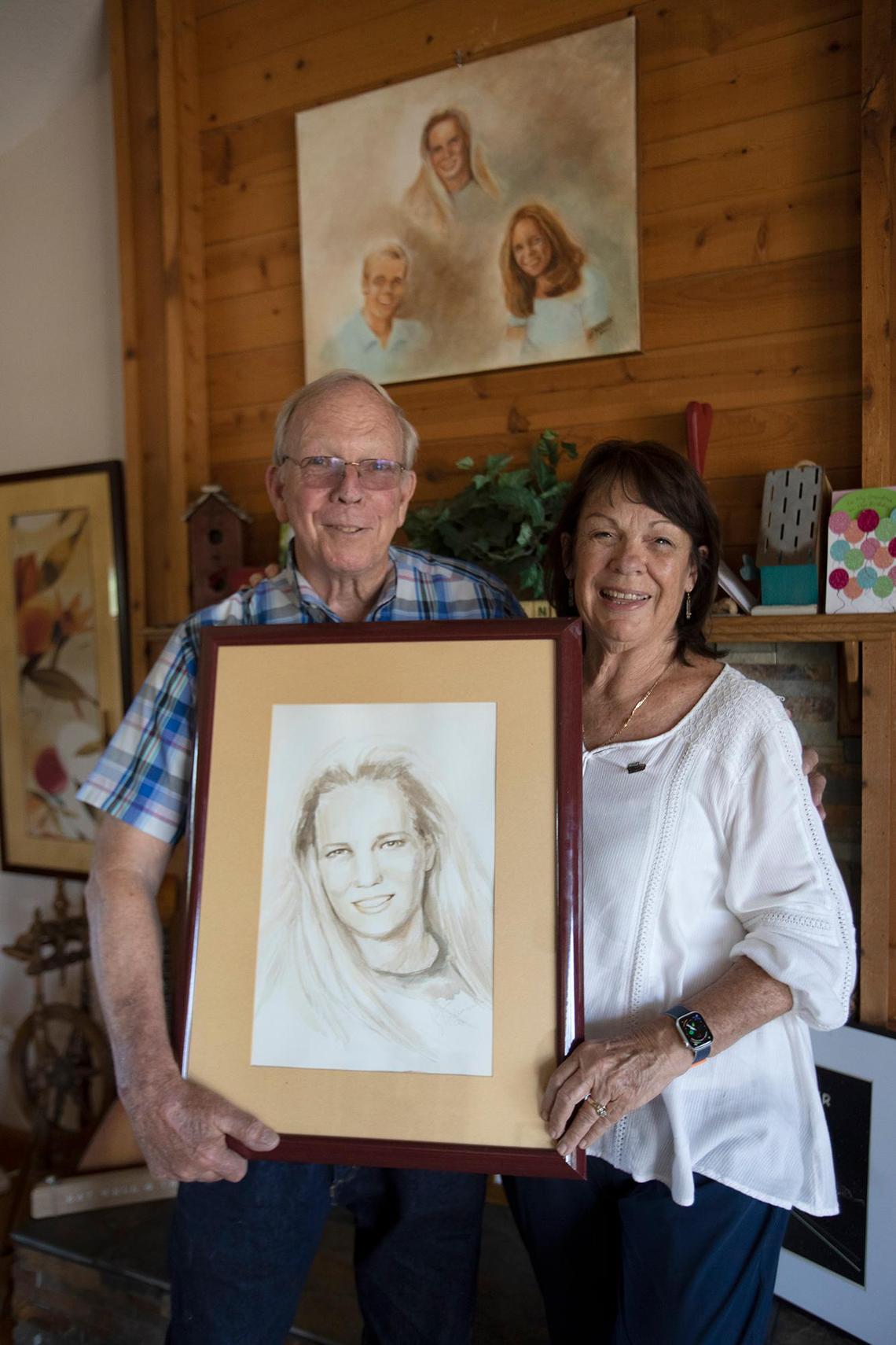 Stan and Denise Smart hold a portrait of their daughter, Kristin, at their Stockton home on May 24, 2023, in front of a painting of their children created by Stan’s sister, Sandy Rudolph.
