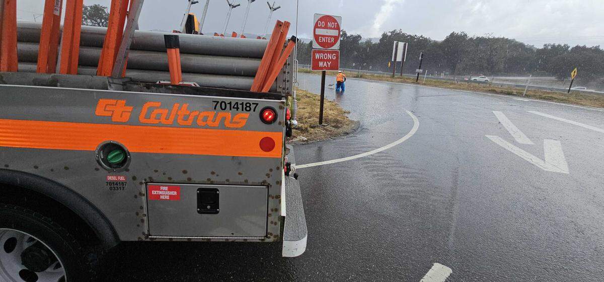 Caltrans employees work to clear the flooded the southbound San Ramon Road exit from Highway 101 in Atascadero on Oct. 14, 2025.