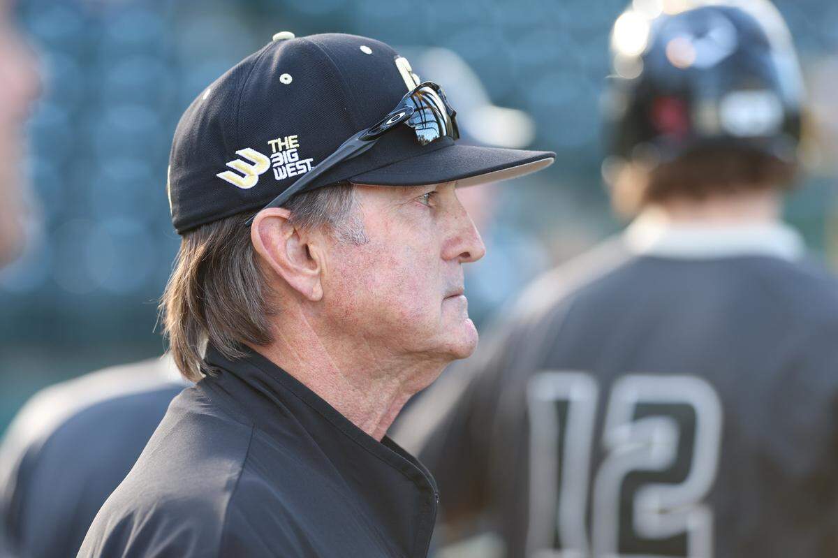 Cal Poly baseball Head Coach Larry Lee stands near the dugout as the Mustangs get set to bat.
