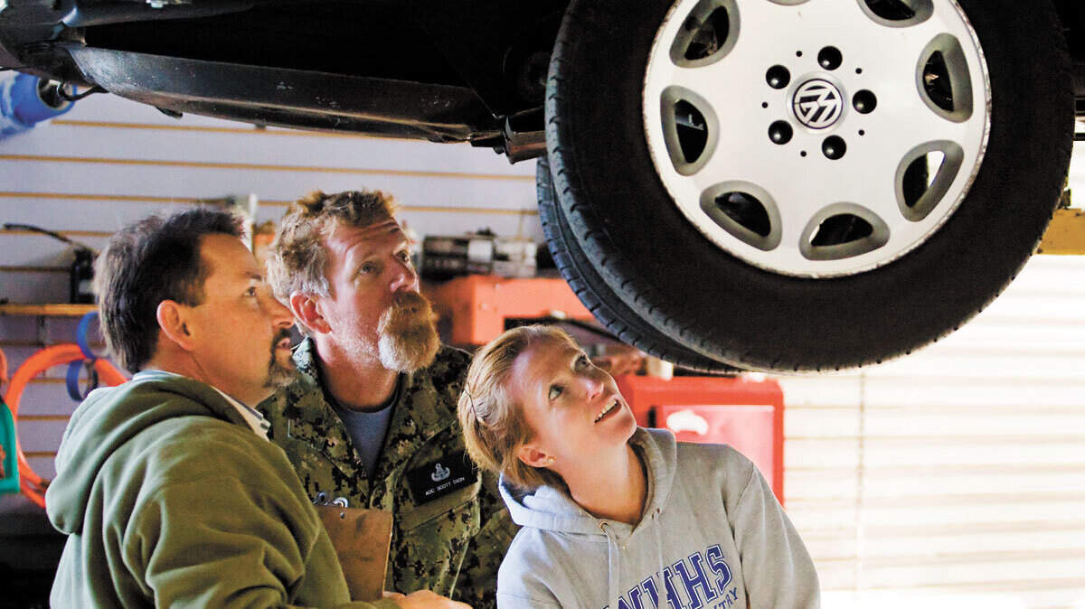 U.S. Navy veteran Scott Dion, center, and his wife, Sarah, look over their Volkswagen Westfalia camper with GoWesty owner Segismundo Lucas Valdes.