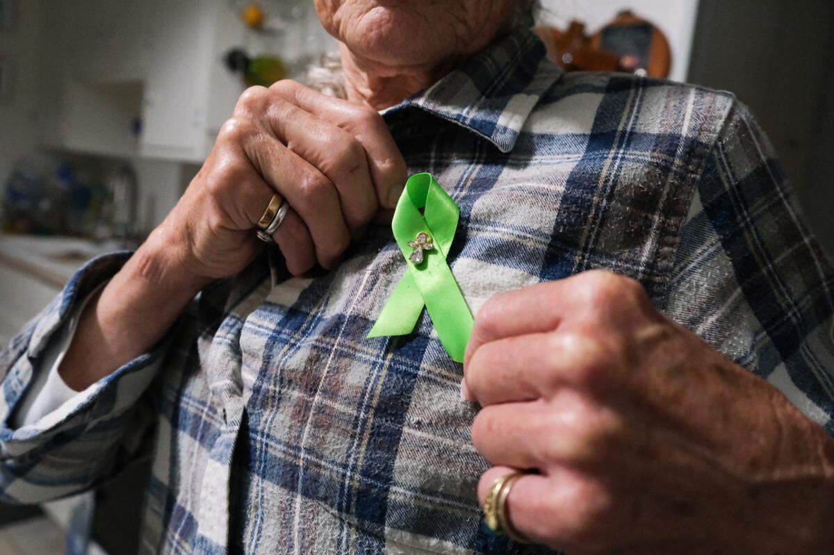 Dawn Marie Anderson shows the green ribbon she places on her shirt every day on Sept. 9, 2024. The green ribbon symbolizes mental health awareness, an issue close to her heart as her son lives with schizoaffective disorder.