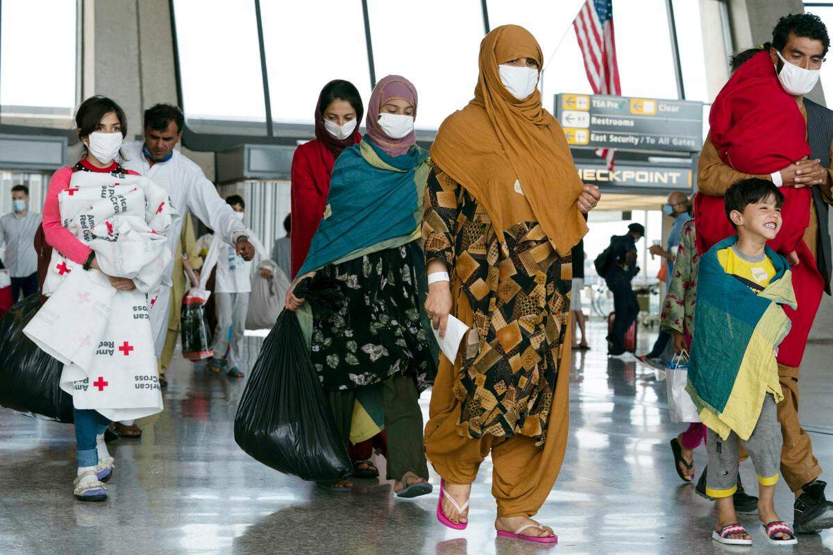 Families evacuated from Kabul, Afghanistan, walk through the terminal before boarding a bus after they arrived at Washington Dulles International Airport, in Chantilly, Virginia, on Thursday, Aug. 26, 2021.