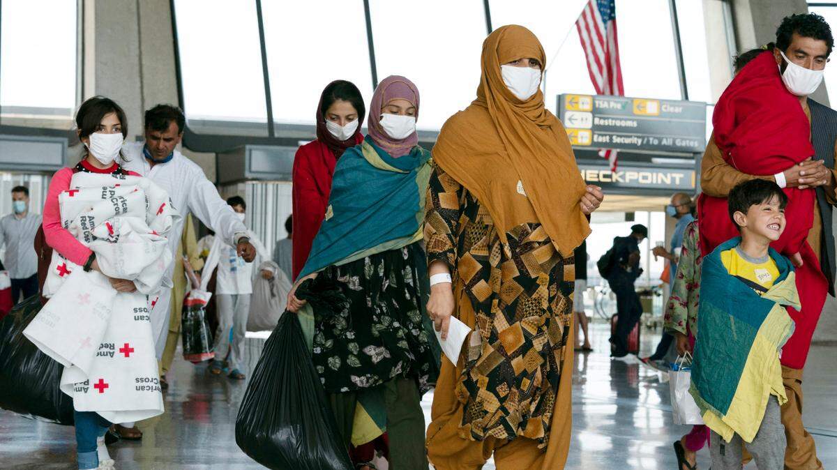 Families evacuated from Kabul, Afghanistan, walk through the terminal before boarding a bus after they arrived at Washington Dulles International Airport, in Chantilly, Virginia, on Thursday, Aug. 26, 2021.