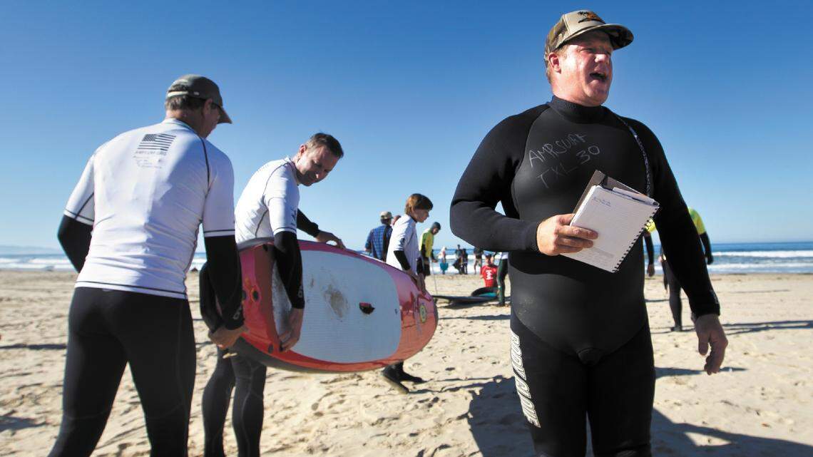 Dana Cummings, co-founder of AmpSurf, directs surfers and volunteers during Operation Restoration at Pismo Beach on Saturday. The program puts disabled people on surf boards and into the waves.