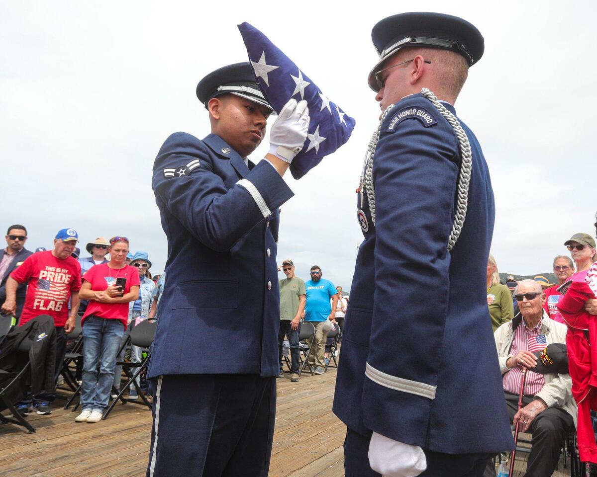 Airman 1st Class Jose Martinez, left and Lt. Tyler Eddy of Vandenberg Space Force Base fold the flag. A standing room crowd attended as Pismo Beach held their Memorial Day ceremony at the Pier on May 29, 2023.