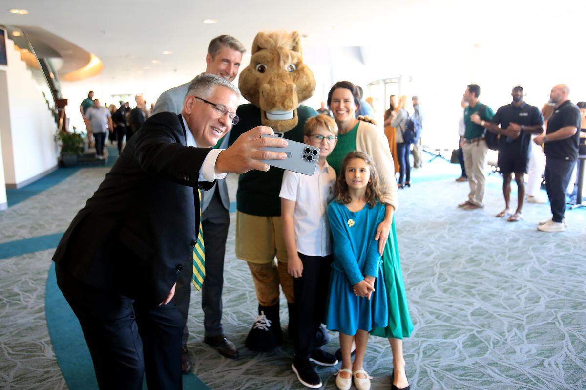 Cal Poly President Armstrong takes a selfie with Carter Henderson and his wife Lindsey, son jack, and daughter Finley.