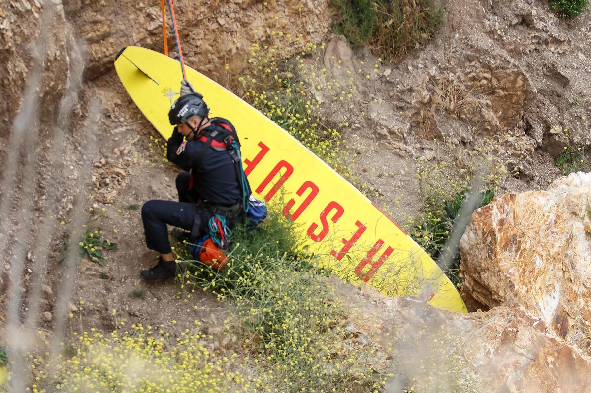 A SLO County firefighter repels down a cliff with a rescue board to retrieve Shell Beach resident Ryan McCormick and his dog Rosie on June 29, 2023.