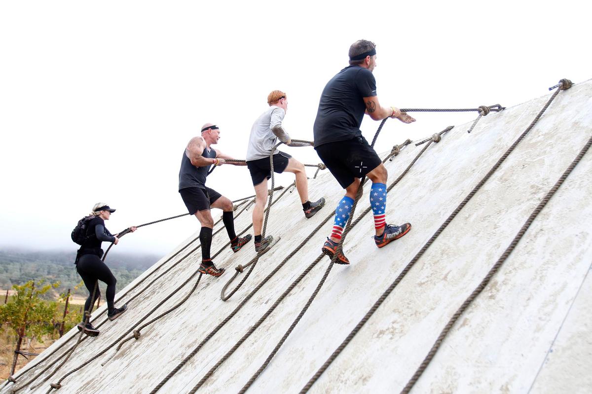 Participants climb up a rope obstacle during the Spartan race event held in Santa Margarita on Saturday, Nov. 2, 2024, featuring a variety of obstacles and courses of different challenge levels.