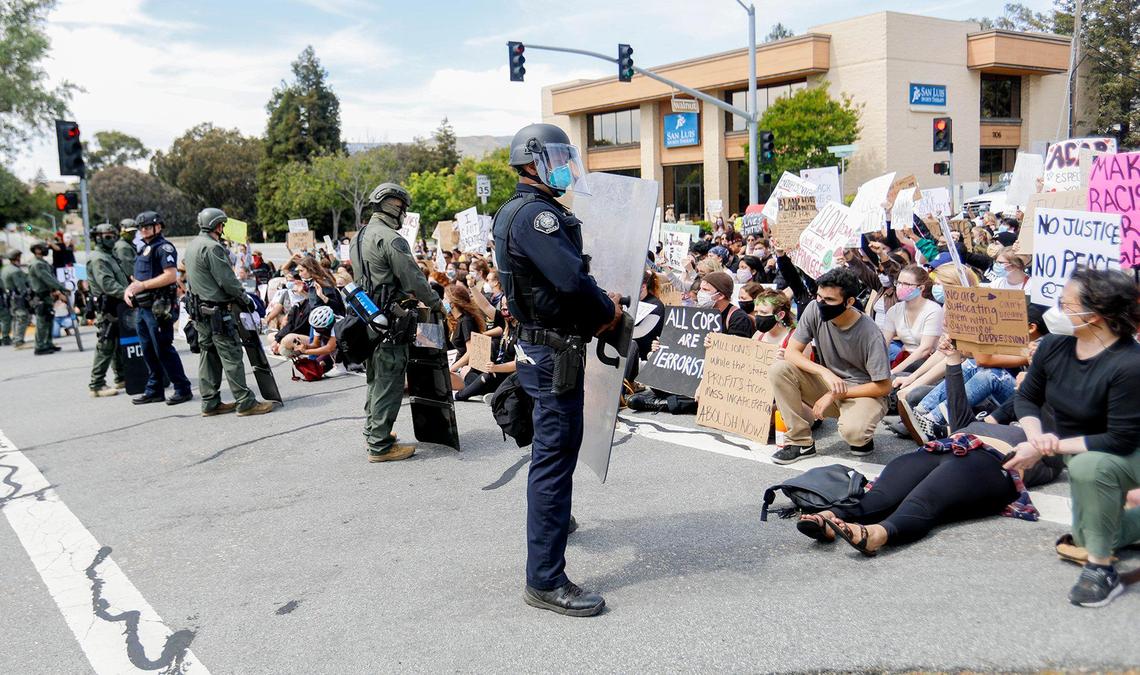 San Luis Obispo police officers cordon off the street from seated protesters next to the San Luis Obispo police station on Walnut Street on June 1, 2020.