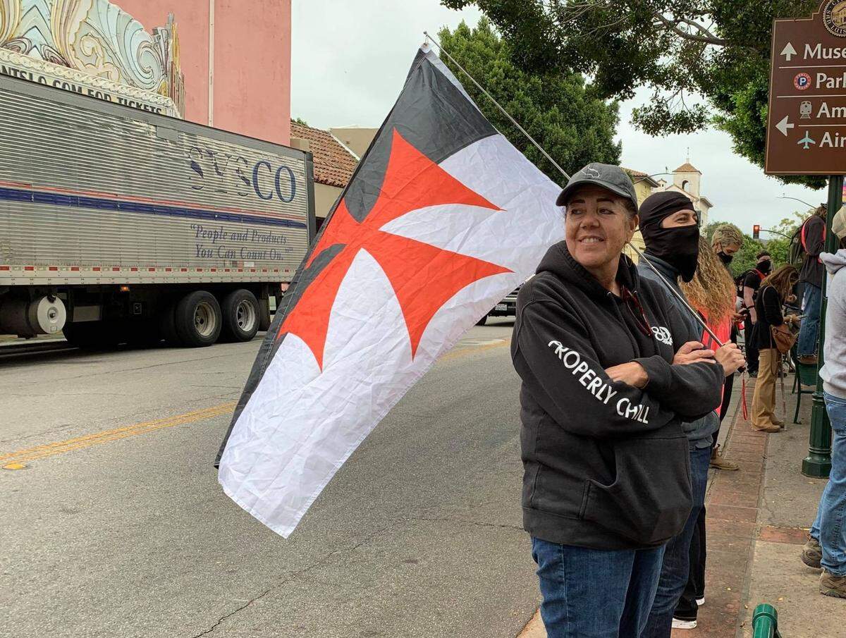 An unidentified man holds a Knights Templar style flag at a Black Lives Matter protest for local defendants in front of the San Luis Obispo Superior Courthouse Thursday, Oct. 22, 2020. The flag is a recognized modern white supremacist symbol.